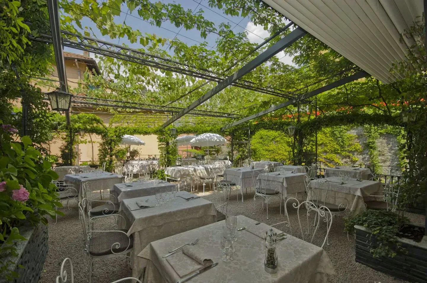 Outdoor dining at Ristorante Bilacus in Lake Como, with vine-covered pergola and elegant tables